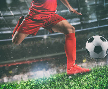 Soccer player kicks the ball vigorously at the stadium